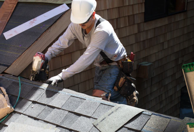 man working on asphalt roof shingles